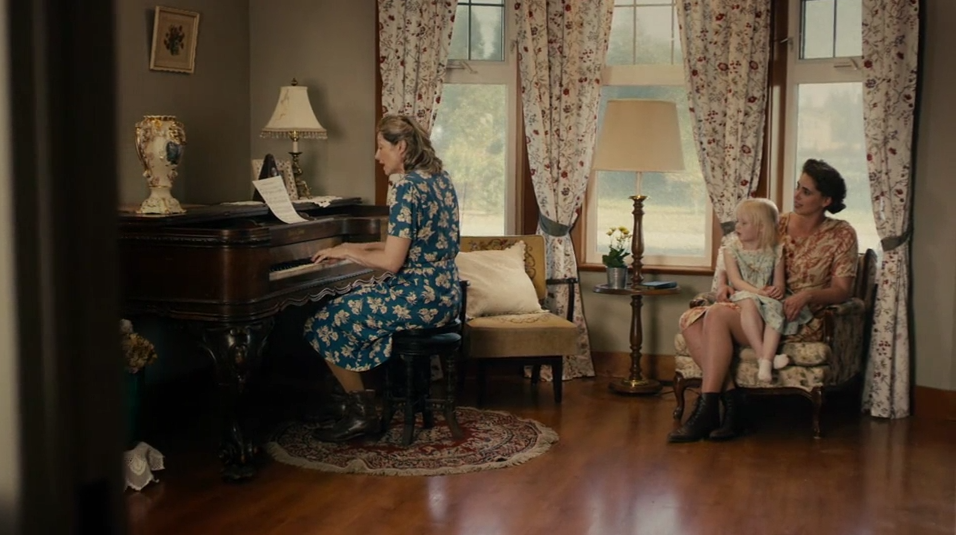 Betty, her mother and Isabel sit around the piano.